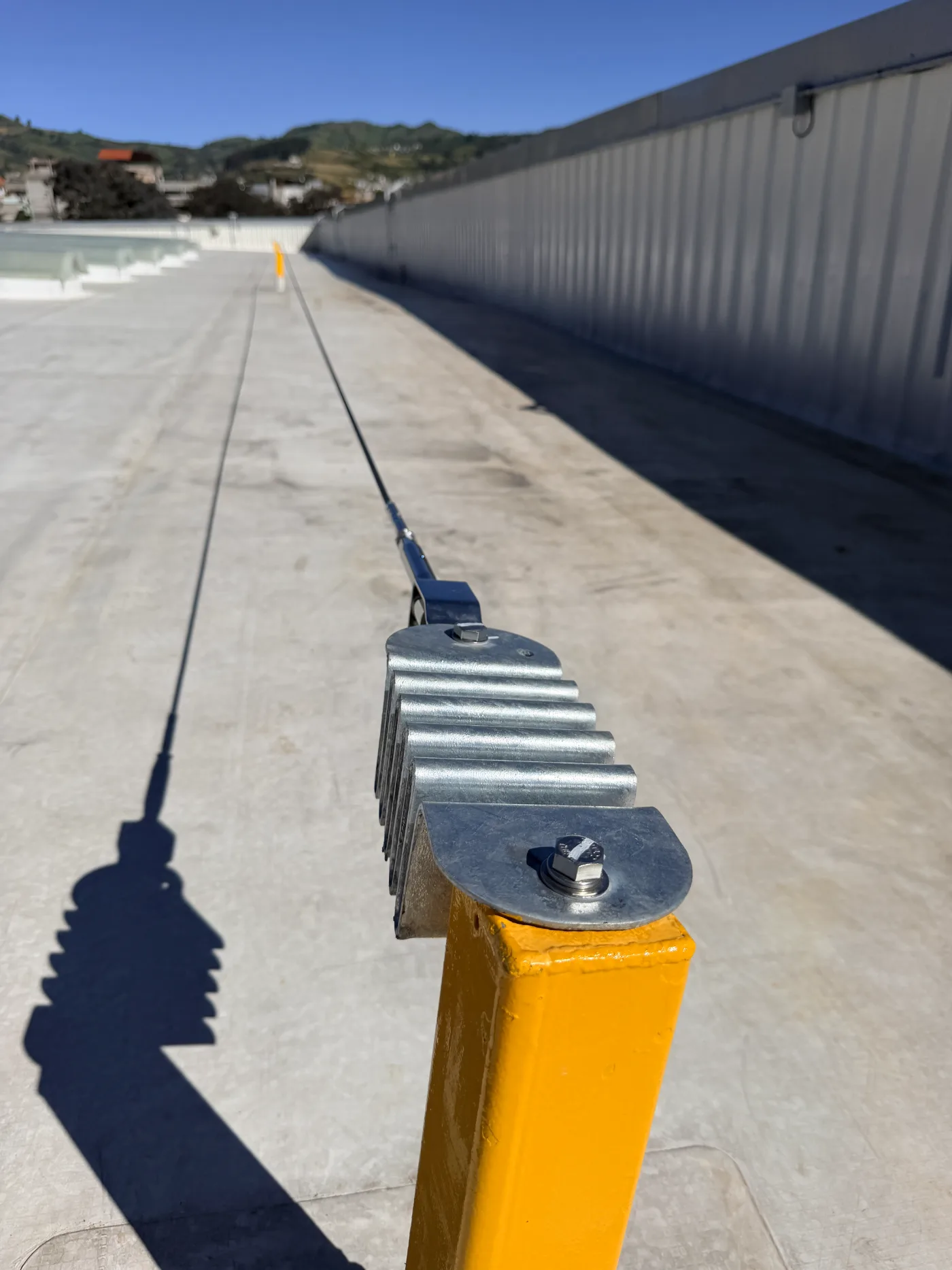 Absorbedor de energía sobre poste amarillo con la línea de vida corriendo a lo largo de la cubierta