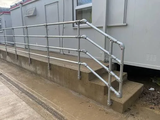 Pasamanos de tubo y accesorio junto a rampa de acceso