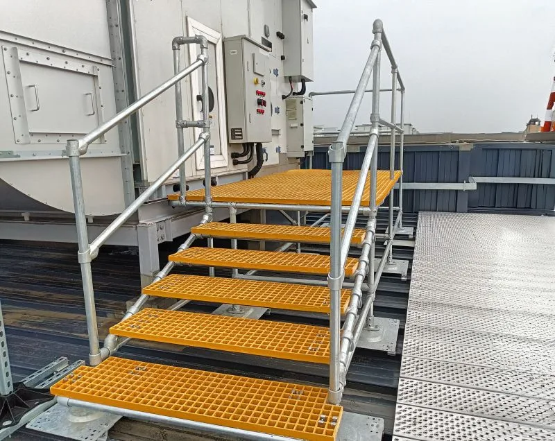 Escalones de acceso con peldaños antideslizantes junto a equipo de climatización
