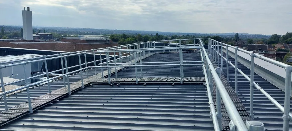 Pasarela elevada sobre cubierta metálica con barandilla continua